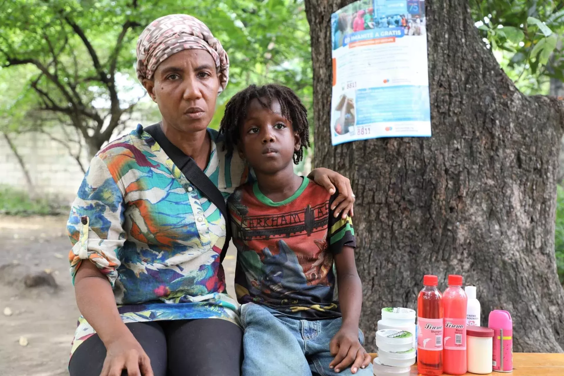 Haiti. A mother and her child sit next to some items they sell at their small store.