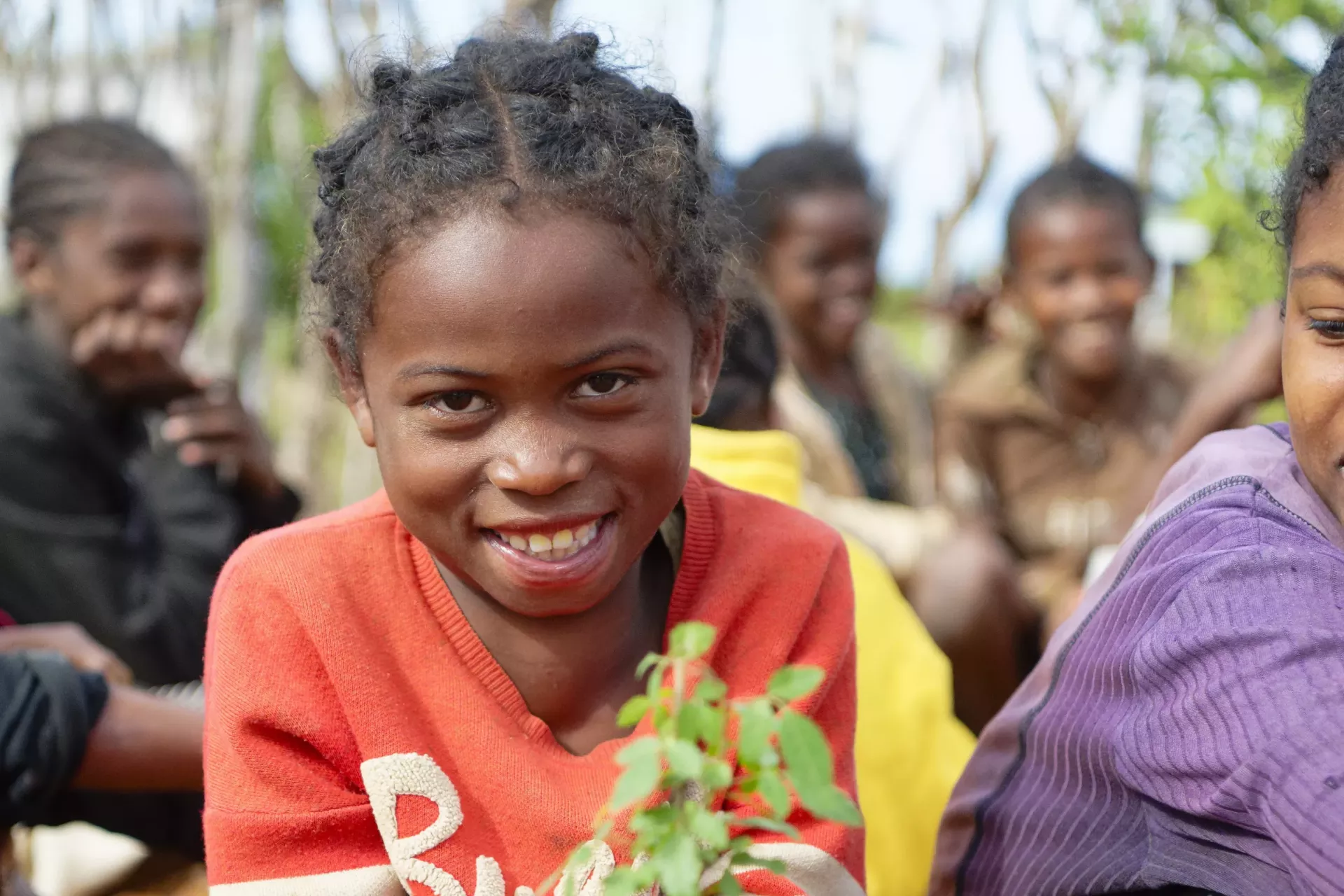Soamanitra Primary Public School, Commune of Tranovaho, Beloha District, Androy Region, Madagascar: portrait of a smiling schoolgirl holding a young tree in her hands.
