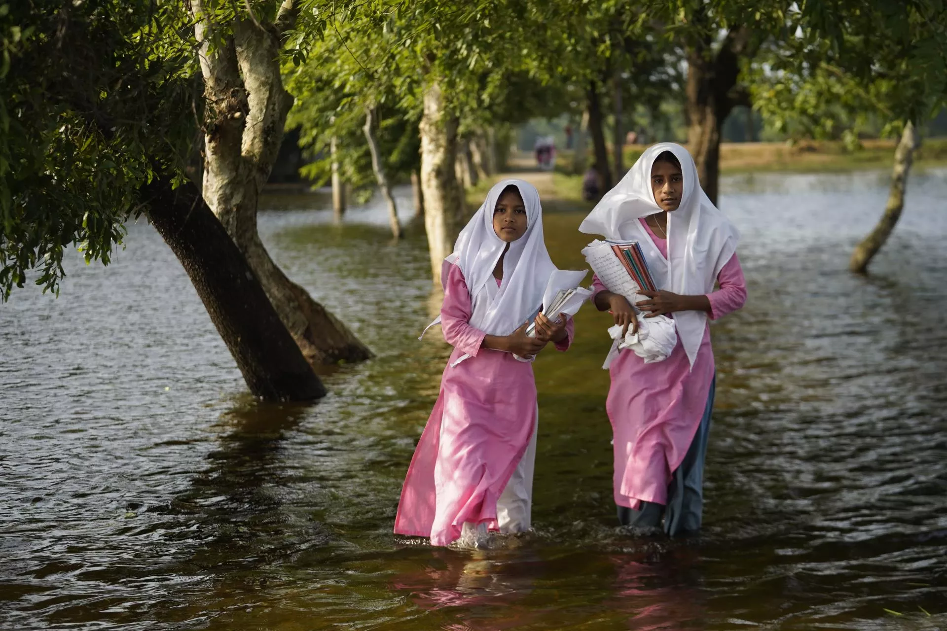 Las ni&ntilde;as caminan a trav&eacute;s de las inundaciones para llegar a su escuela en el noreste de Bangladesh, donde m&aacute;s de cuatro millones de personas se vieron afectadas por las grandes inundaciones de mayo de 2022.