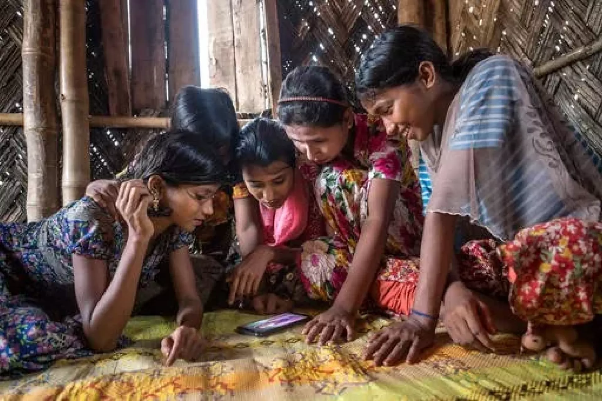 Refugee girls in Bangladesh playing on a cell phone.