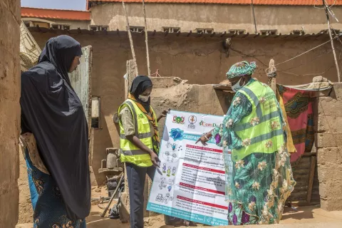 Niger. Workers share information on a poster about COVID-19.