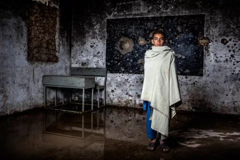 Une fille se tient debout dans une salle de classe détruite 