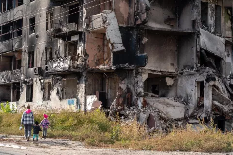 Ukraine. A family walk past badly damaged buildings in Borodianka, Ukraine.