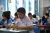 Sarm, 13, writes at his desk during class, surrounded by classmates. 