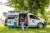 A mother and daughter are met by a woman wearing a UNICEF jacket in front of a van converted into a mobile unit.