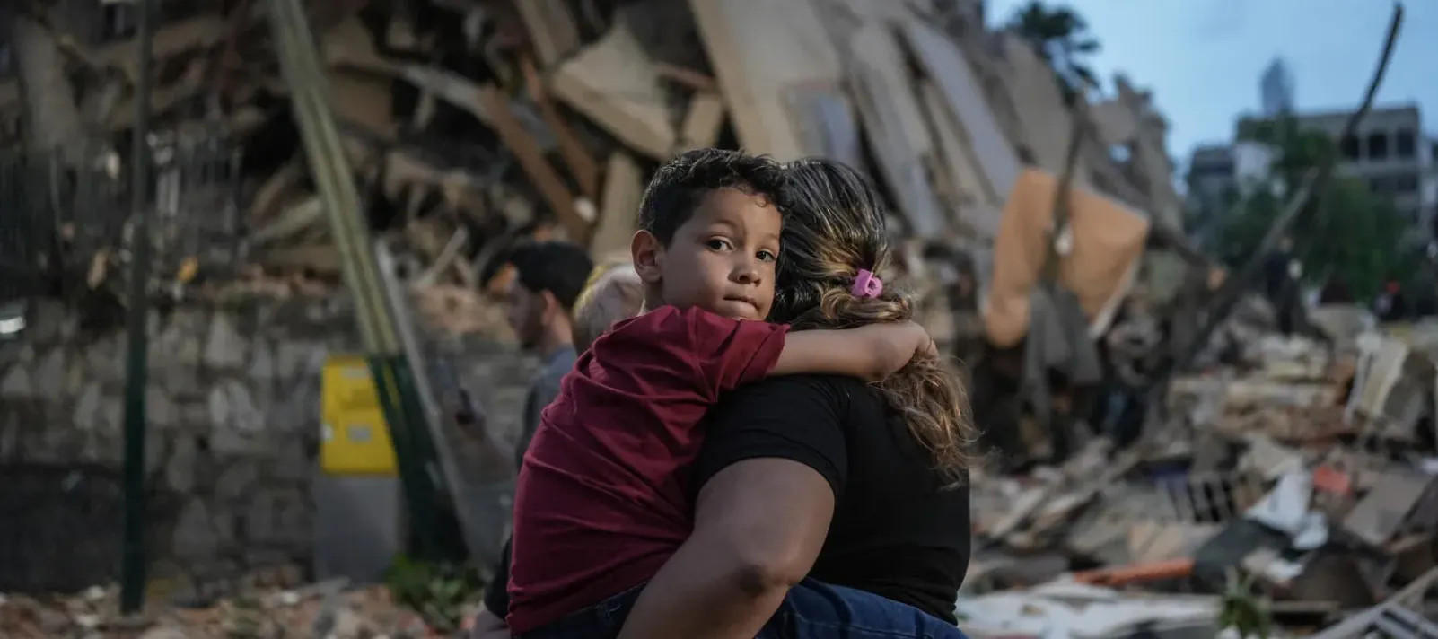 A woman holding a young boy in Caracas, Venezuela, walks past a collapsed building following powerful twin earthquakes on 25 June 2026. 