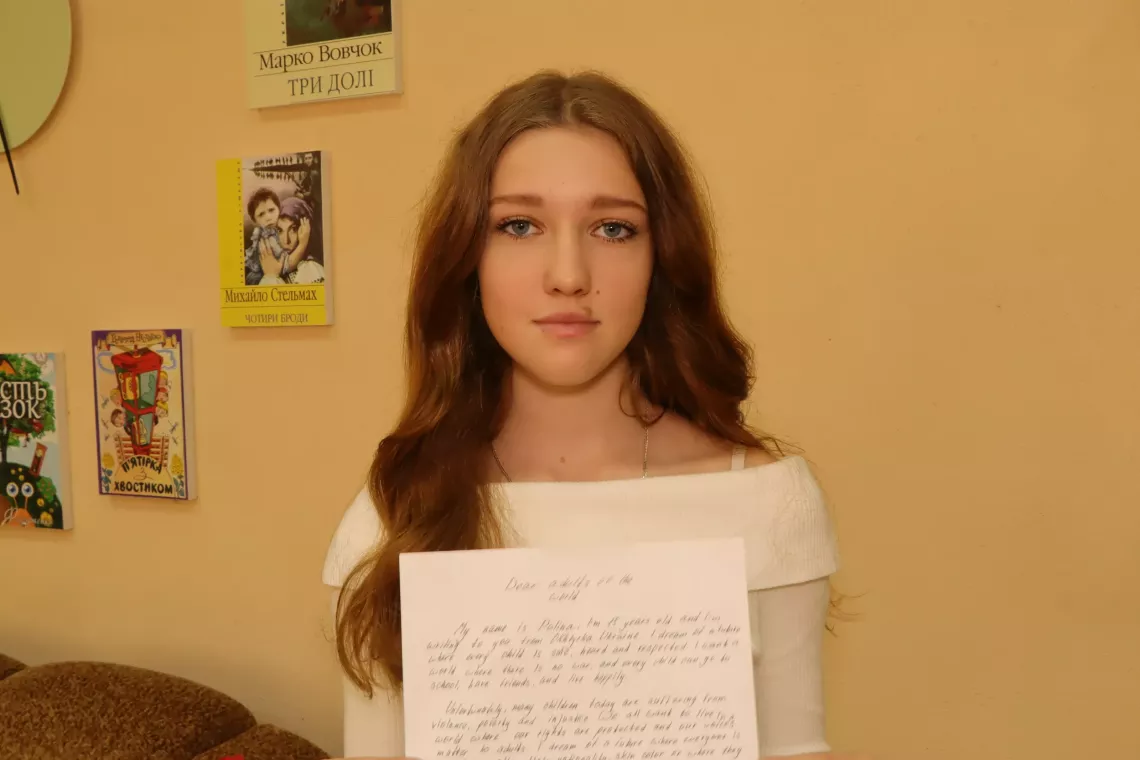 A girl in Ukraine holds her letter to adults. 