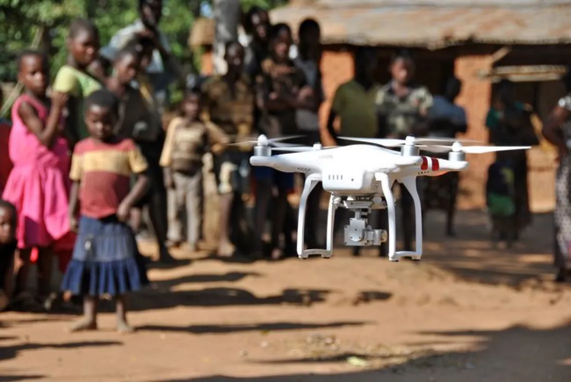 Children in Malawi watch a drone demonstration
