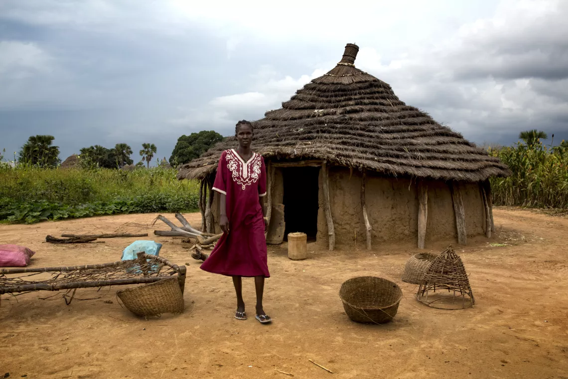A woman stands outside a house in South Sudan