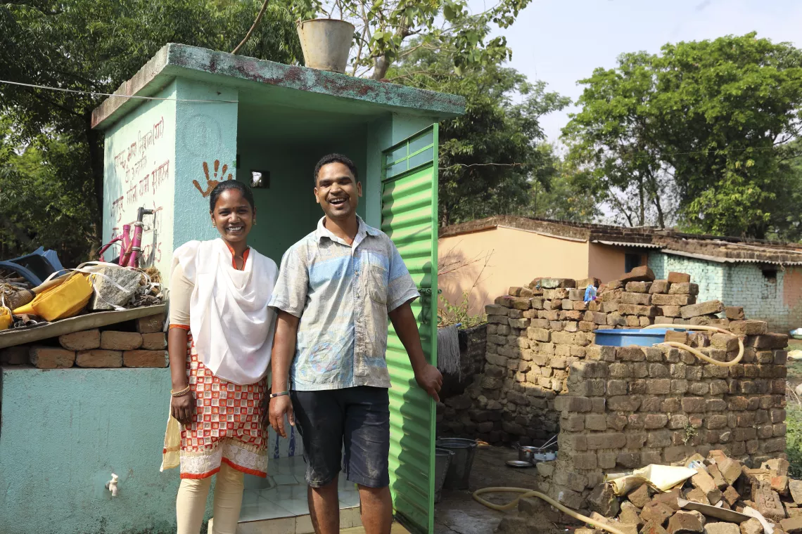 A man and woman stand outside a latrine, India