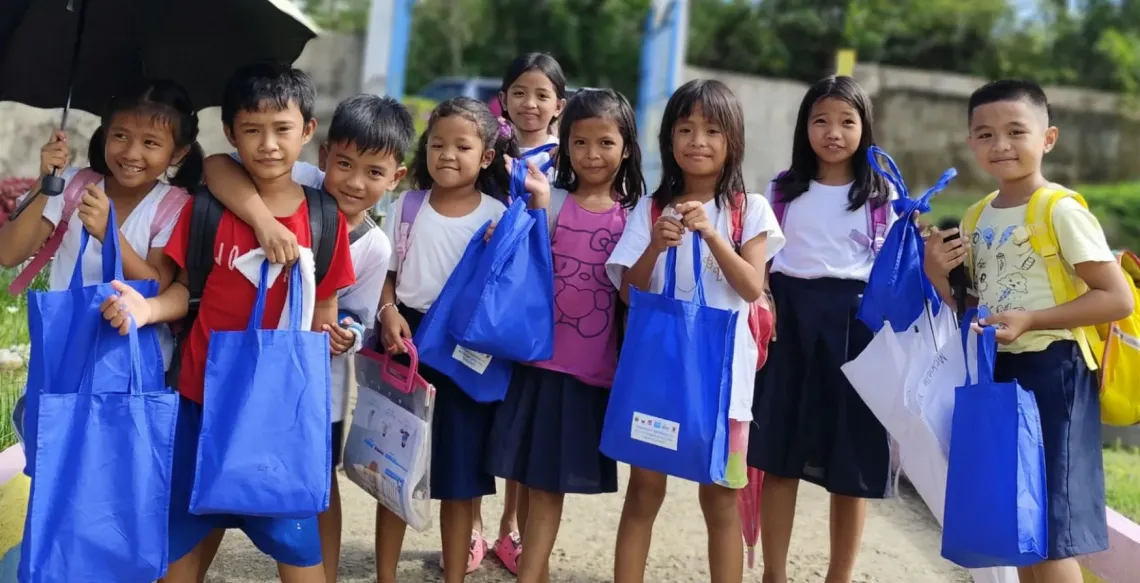 A group of children holding blue bags