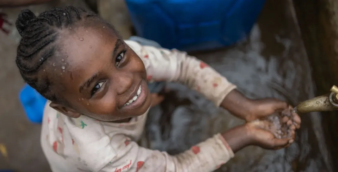 A child at an outdoor water tap
