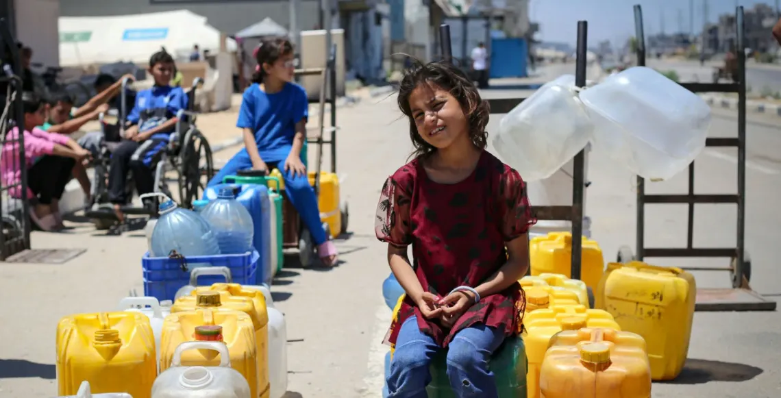 Children sit amongst empty jerry cans