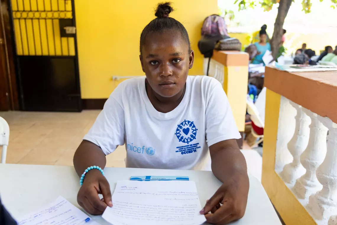 A girl sits at a desk outside looking serious and determined. 
