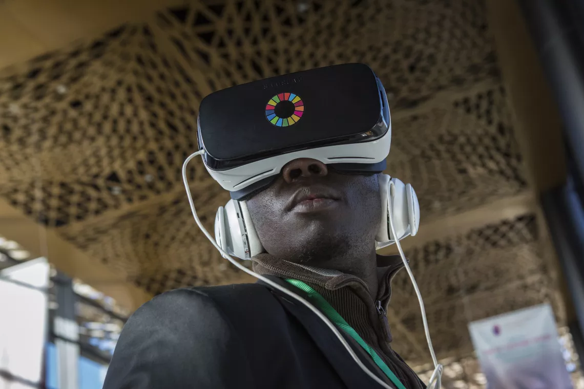 A journalist wears a headset and watches a virtual reality video at a UNICEF exhibition in Senegal