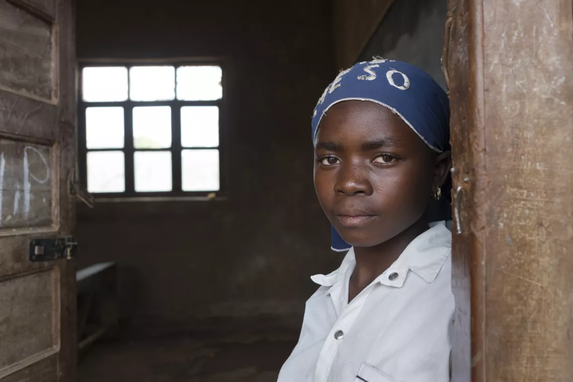 DRC. A girl stands in front of her classroom.