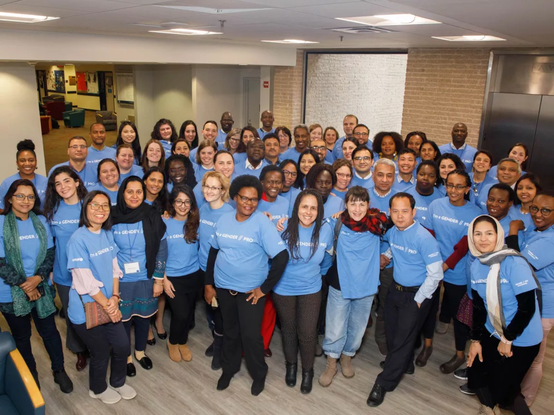 A group of people standing together in a room wearing matching blue t-shirts with the words "I'm a gender pro" on them.
