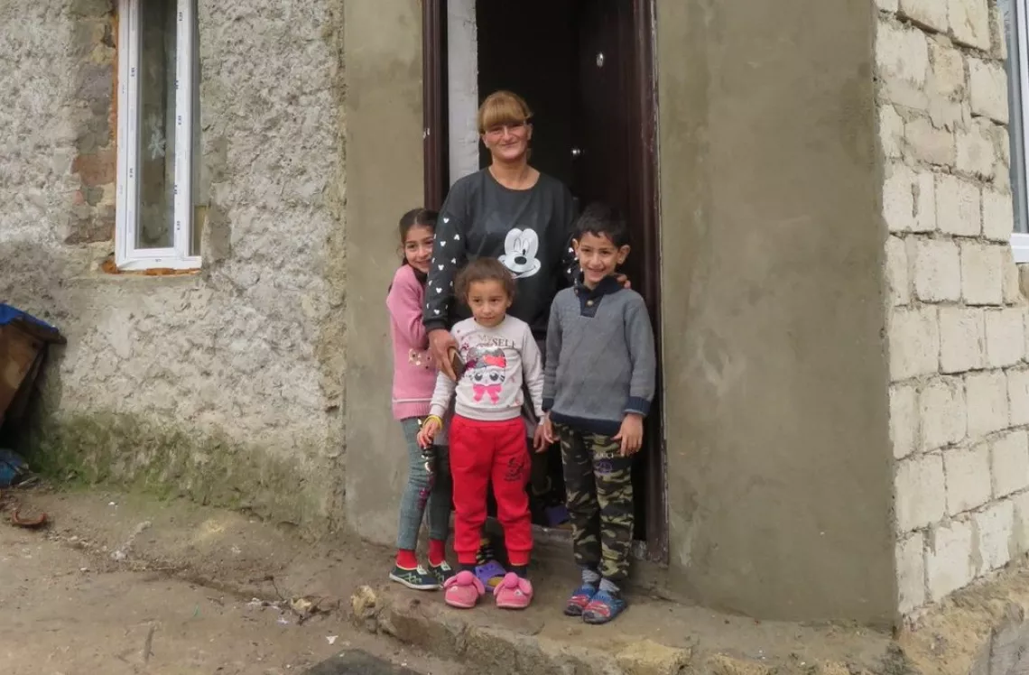 Georgia. A family stand outside their home.