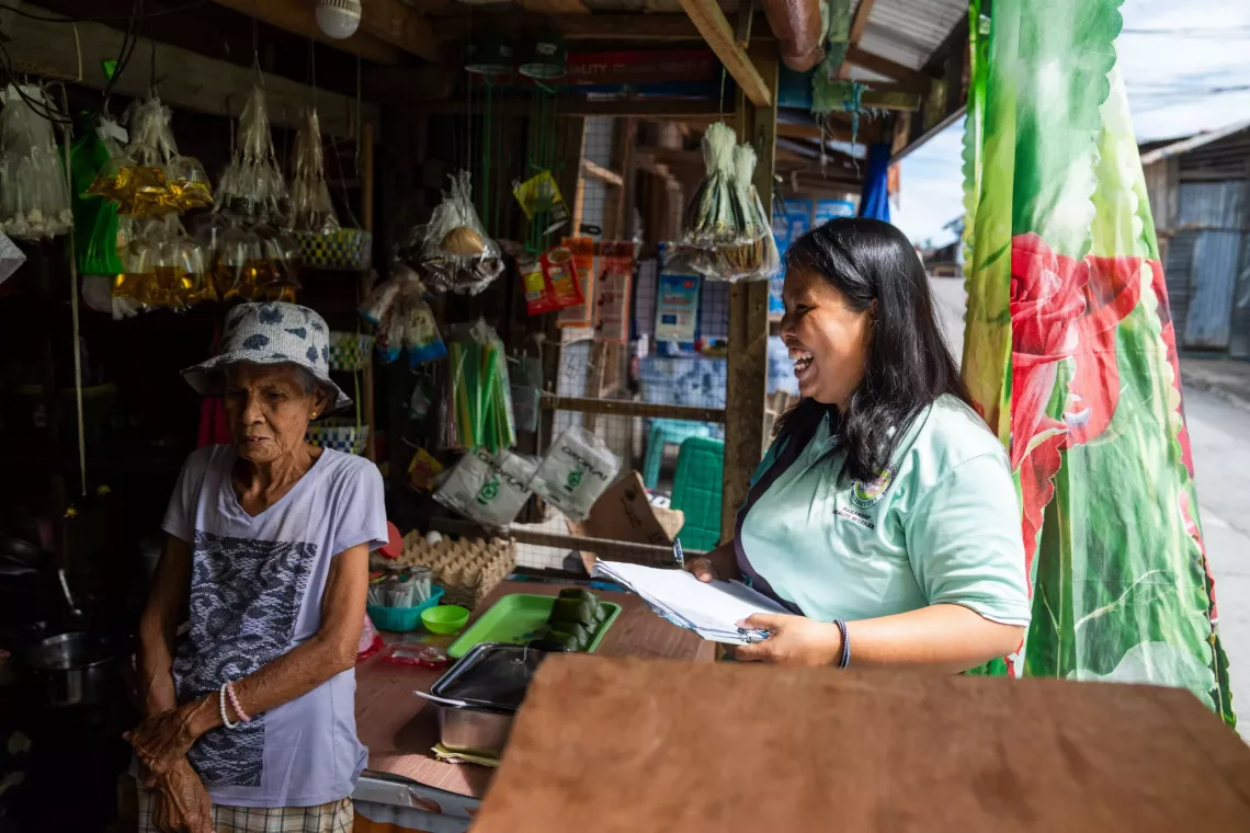 A health worker laughs as she talks to a local shopkeeper