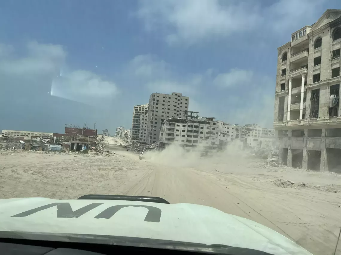 UN vehicle drives through destroyed city. 