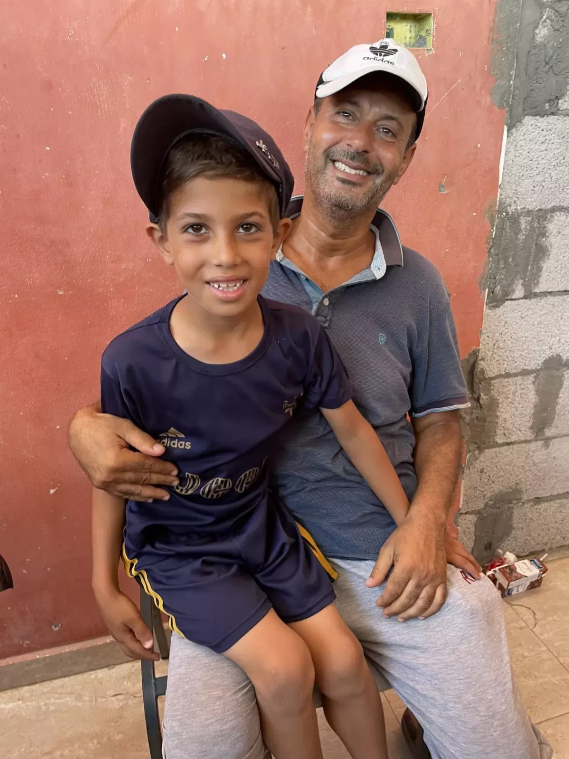 A son sits on father's lap smiling. 