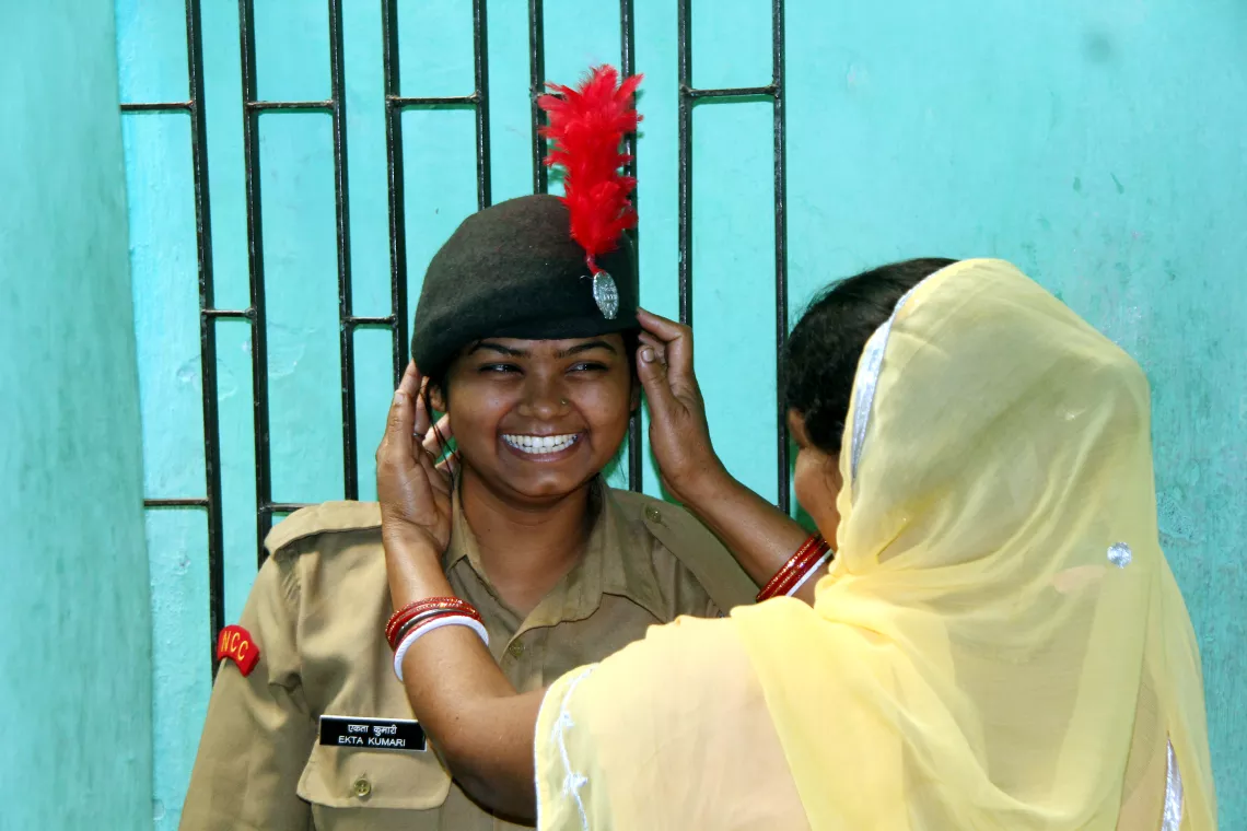 A girl proudly wears her National Cadet Corps uniform, while her mother lovingly adjusts her beret.
