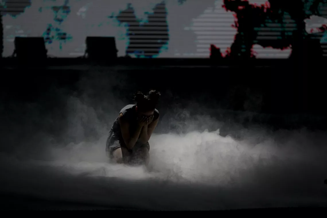 Air pollution in Mongolia: A dancer kneels down on stage surrounded by smoke. 