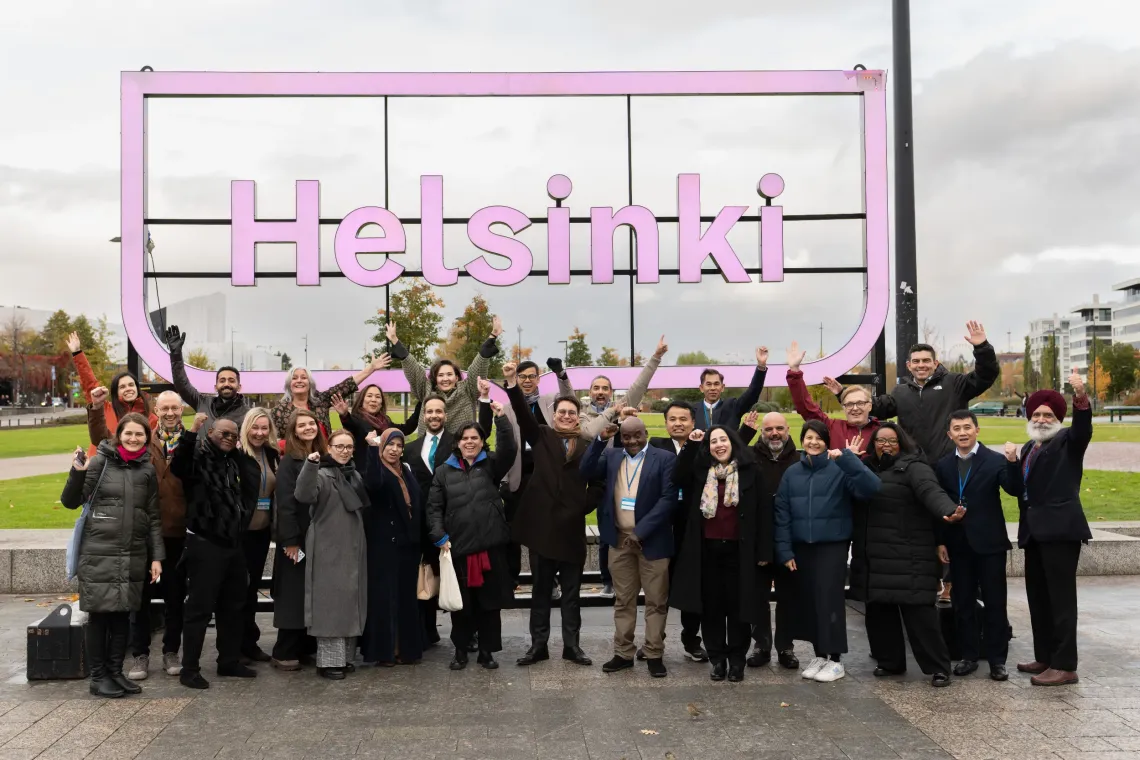 Diverse group of happy innovation camp participants in front of a Helsinki sign