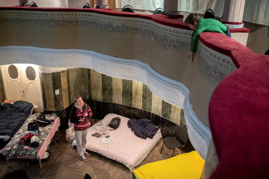 Ukraine. A woman looks up to the balcony from the floor of a theatre.