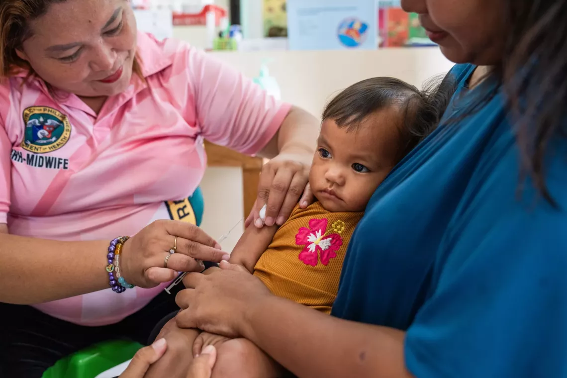 A child in her mothers arms receives a vaccine jab