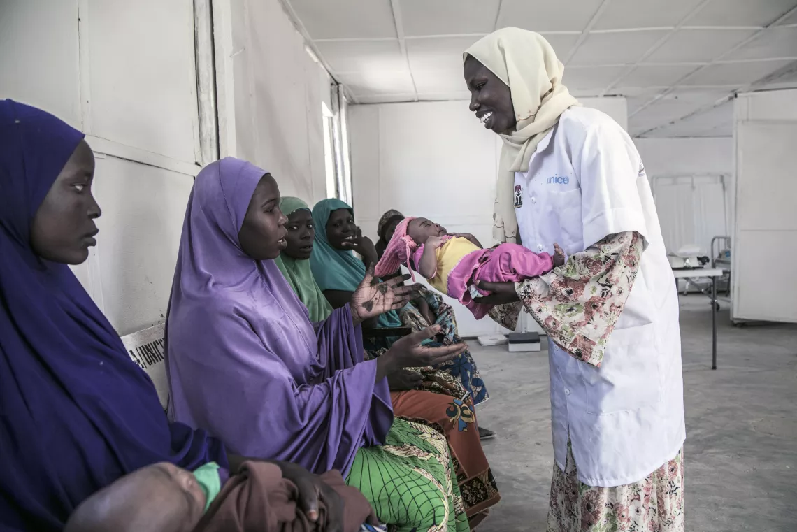 A midwife hands a newborn to her mother, Nigeria