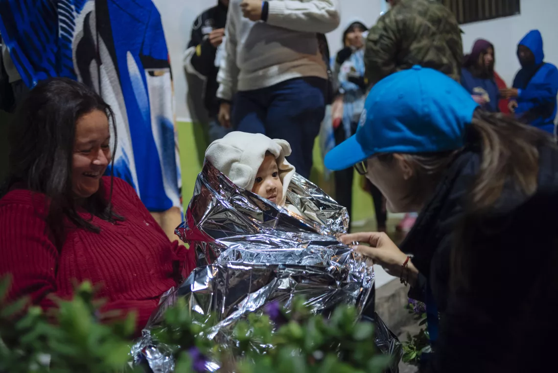 A baby receives a thermal sheet from UNICEF officials in Ecuador.