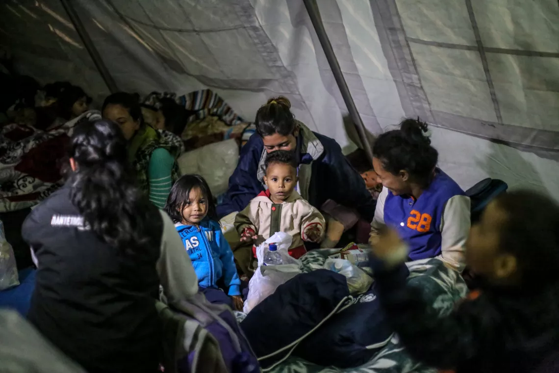 Migrant children and mothers gather at a rest tent in Ecuador. 