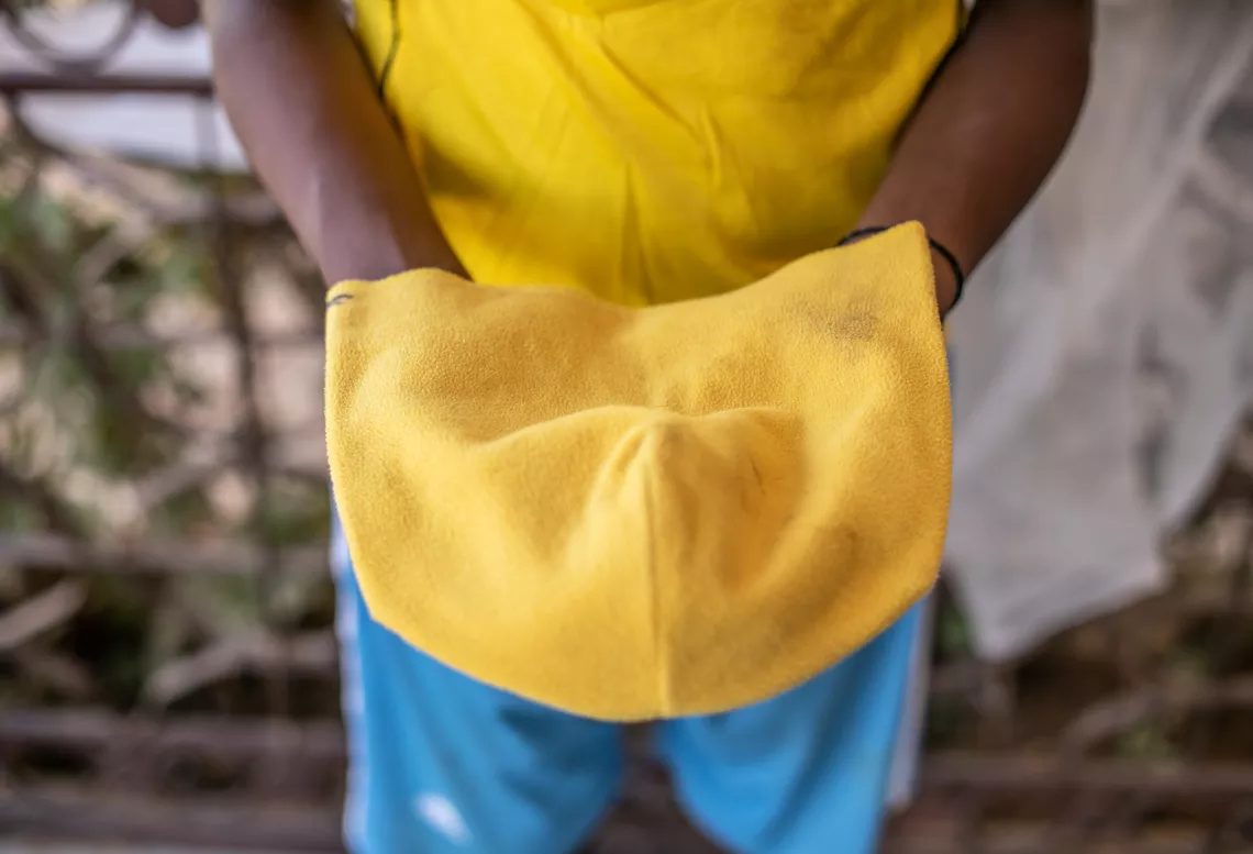 Niger. A teenager holds up a yellow hat.
