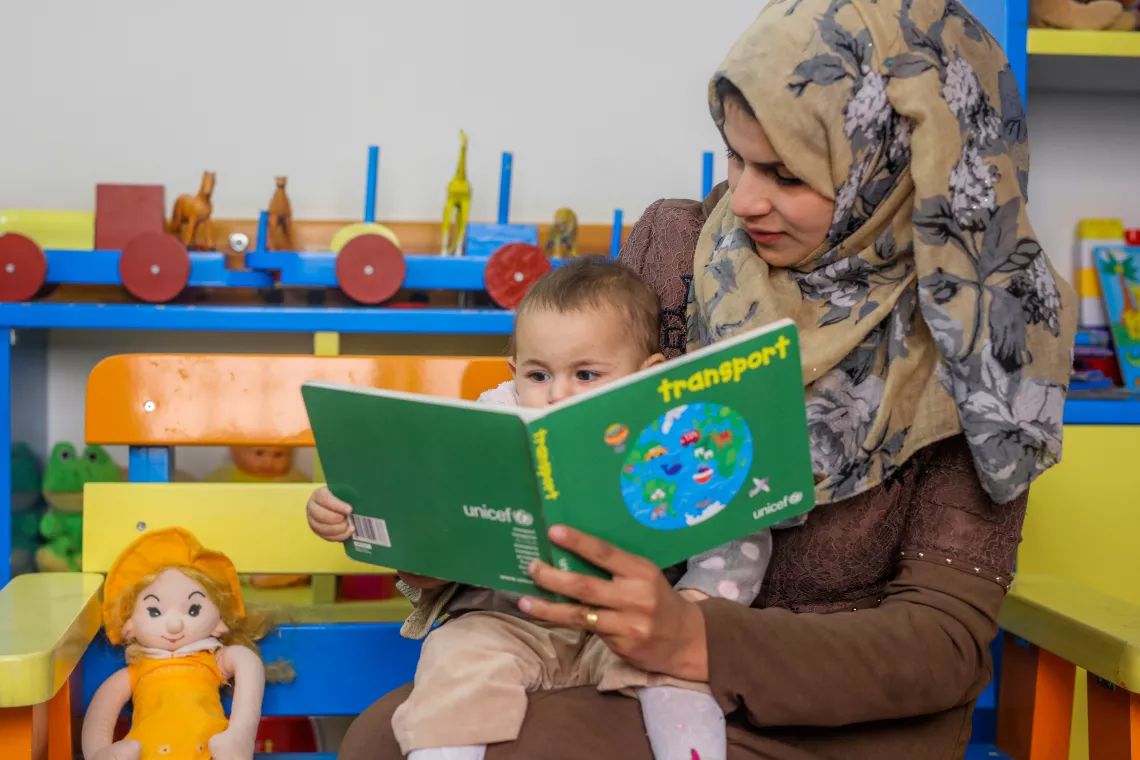 Une institutrice lit un livre à un jeune enfant dans une salle de classe