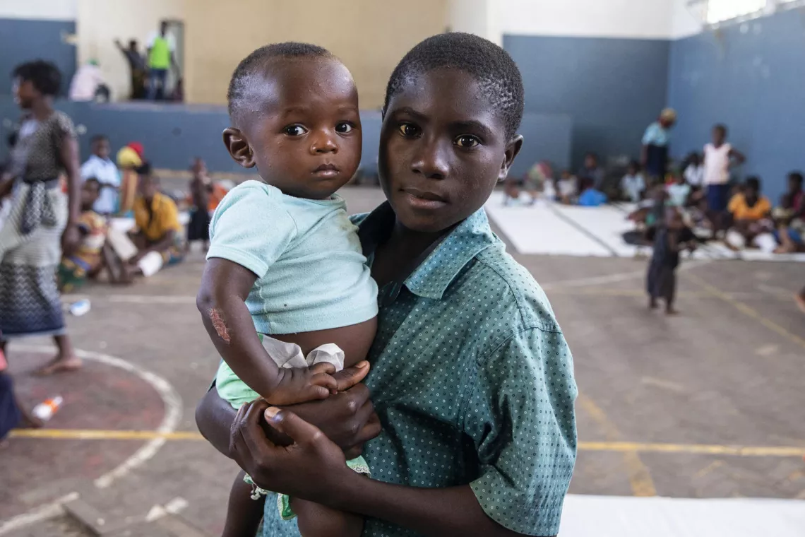 A boy carries an infant