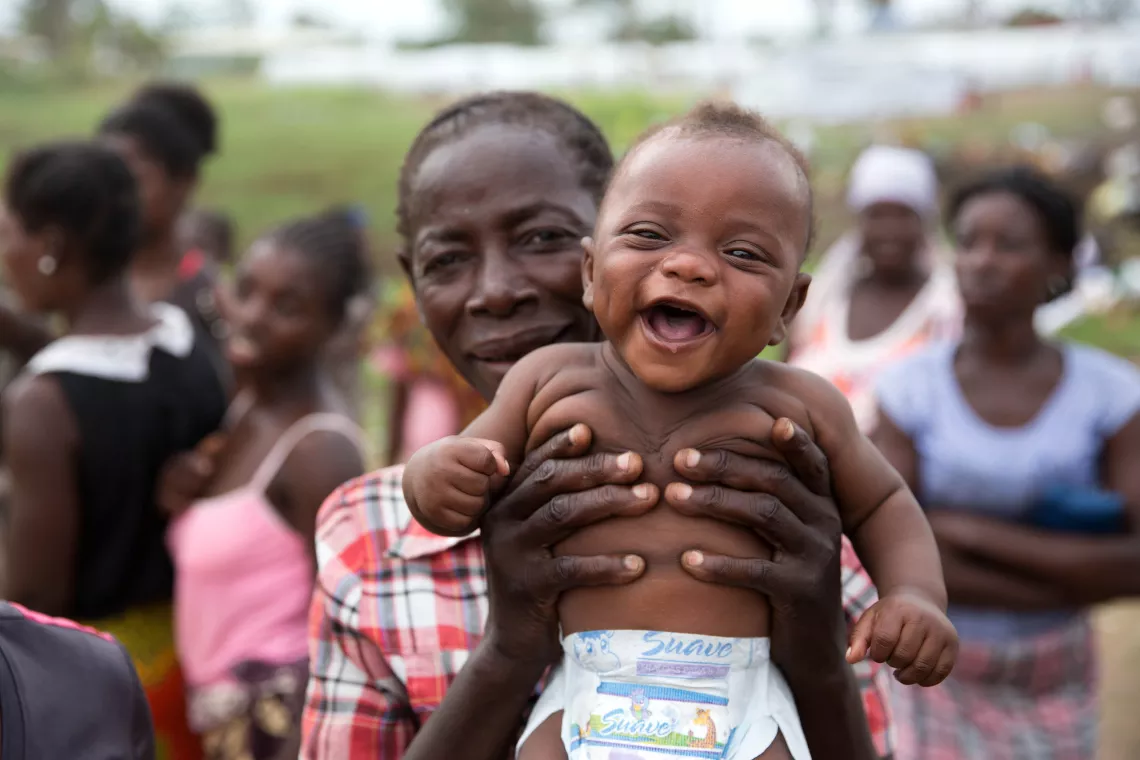 Une m&egrave;re porte son enfant alors qu'il sourit.