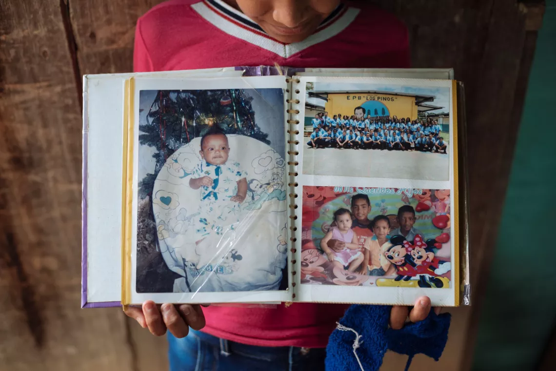 Colombia. A girl holds out a family photo album.
