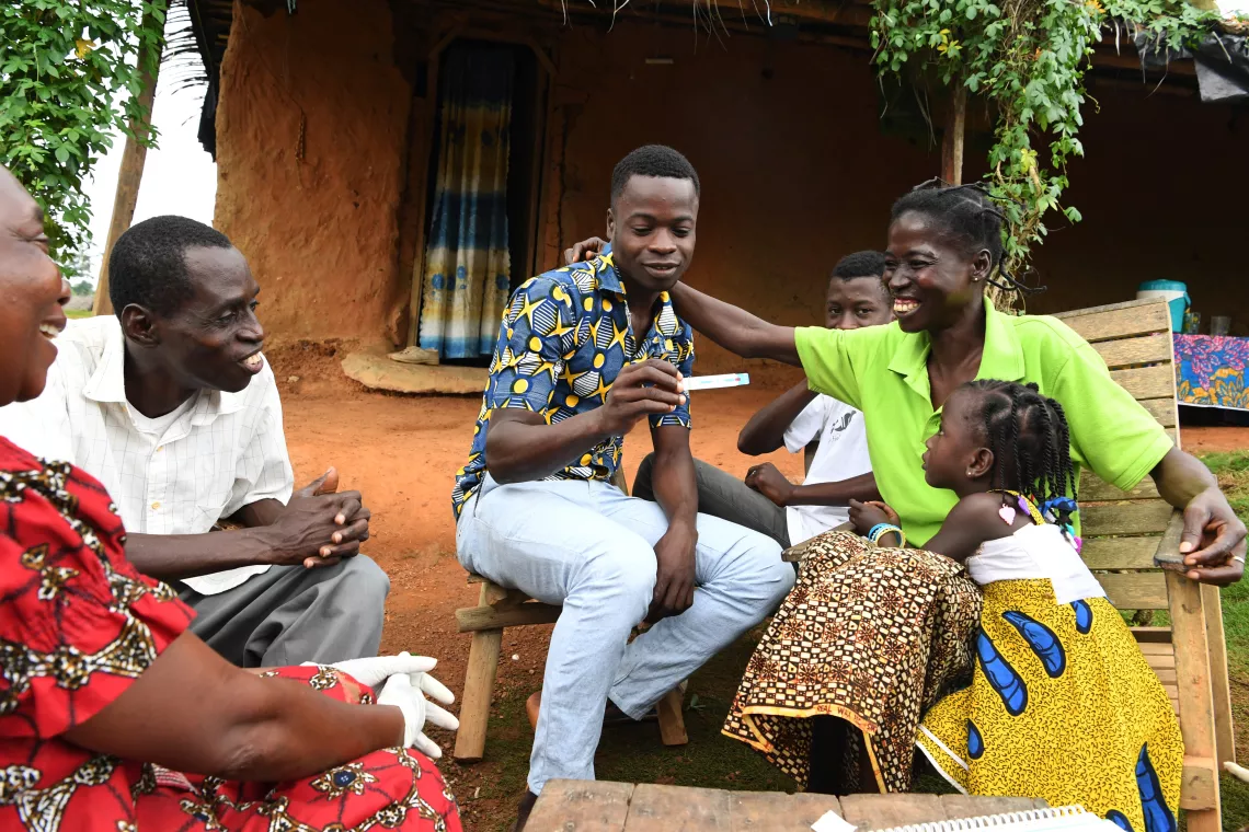 Des adultes et des enfants sont assis devant leur maison, Cote d'Ivoire.
