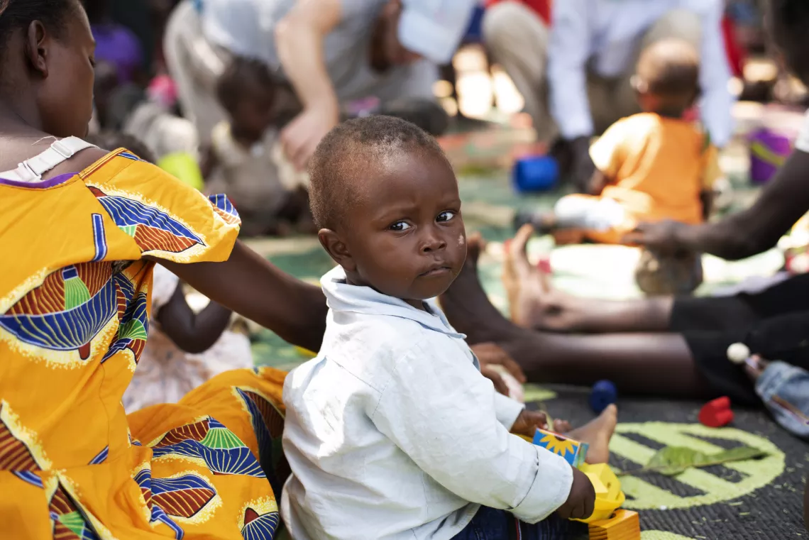 South Sudan. A boy sits outside with his mother.
