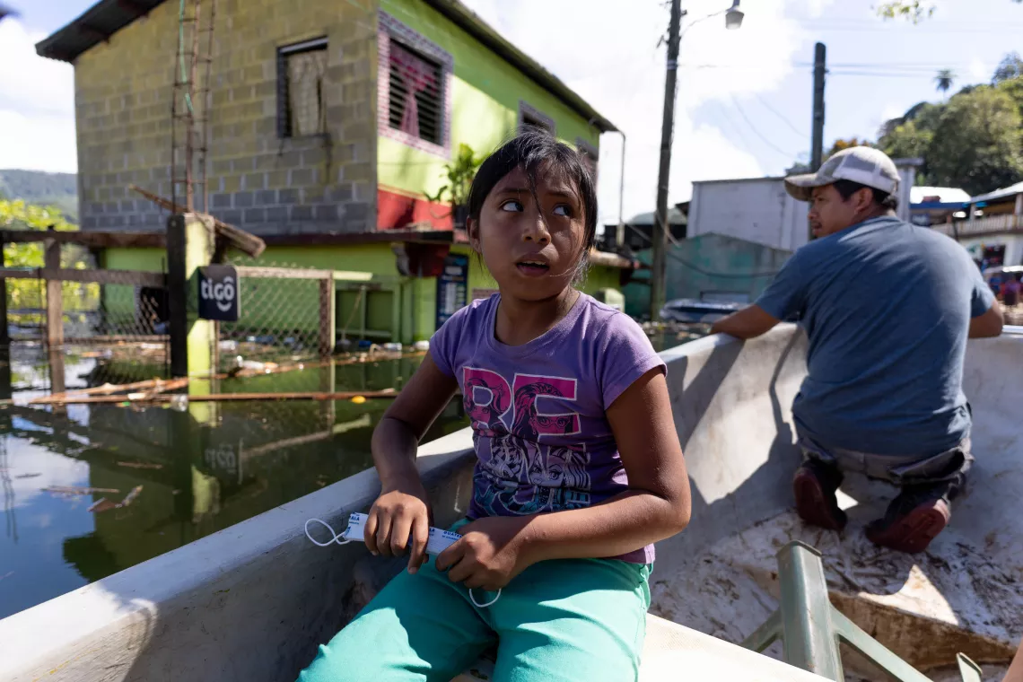 Guatemala : Une jeune fille est assise dans un bateau qui passe pr&egrave;s de ce qu&rsquo;il reste de son &eacute;cole inond&eacute;e.