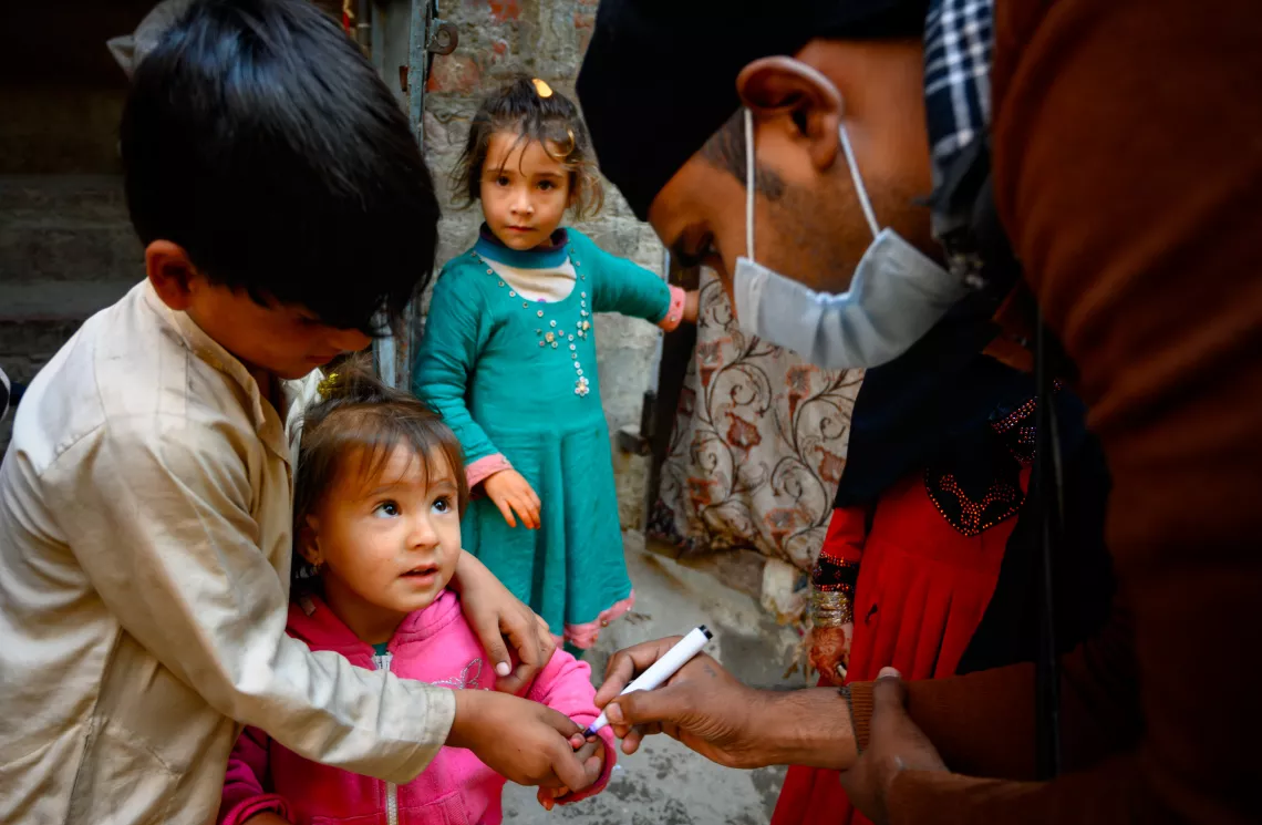 Subhan, a polio vaccinator in Lahore, Pakistan, marks the finger of a two year old girl after providing her the polio vaccine.