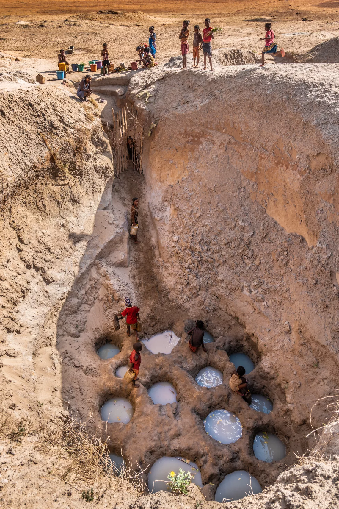 Children collect water from small holes dug within wells inside an almost-dry source in the drought-stricken south of Madagascar