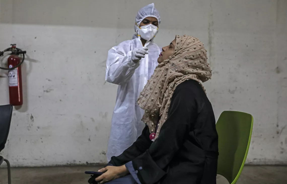 A healthcare worker in Mumbai, India, takes a nasal swab, while testing for COVID-19.