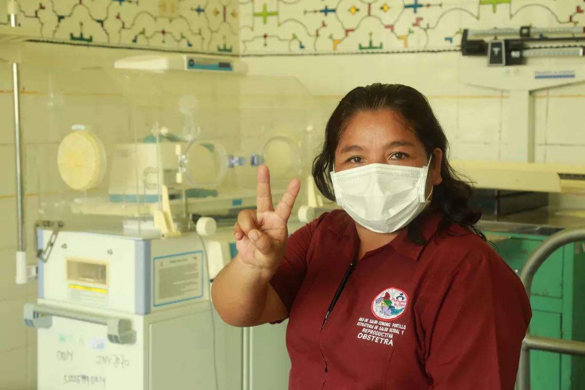 Peru. A health care worker holds up her fingers in the vaccinated sign.