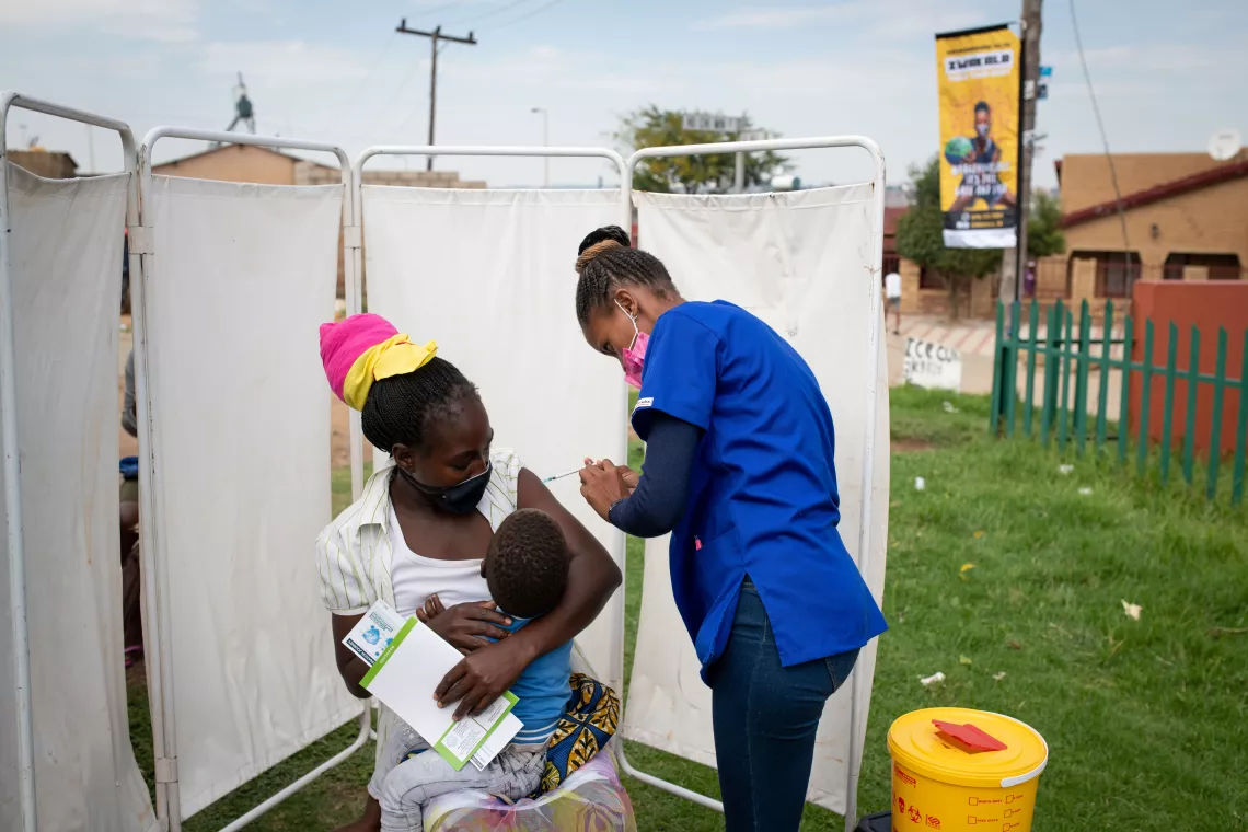 On 10 February 2022, Anathi Wangisi, a professional nurse with the Gauteng Department of Health, administers a COVID-19 vaccine to Theresa Sithole at a pop-up vaccination site in Rebonwe Park in Ivory Park, Thembisa, South Africa.