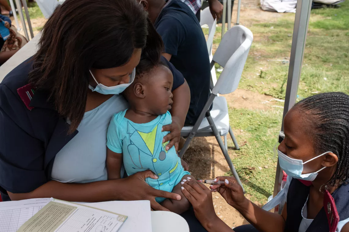 Nurse Siyanda Serwalo, who is pictured on the left, helps to administer a measles vaccine to 6-month-old Lwazi Nhlapo at the pop-up clinic in Ivory Park.