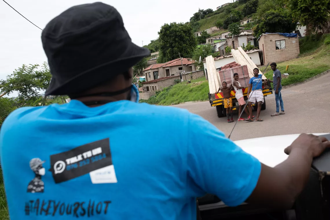 Siyabonga Maphumalo, a mobilizer with the Zwakala campaign, rides on the back of a truck carrying PA equipment and encourages community members to visit a pop-up vaccination clinic near Ntuzuma-New Road taxi rank in Ntuzuma, Durban, South Africa.