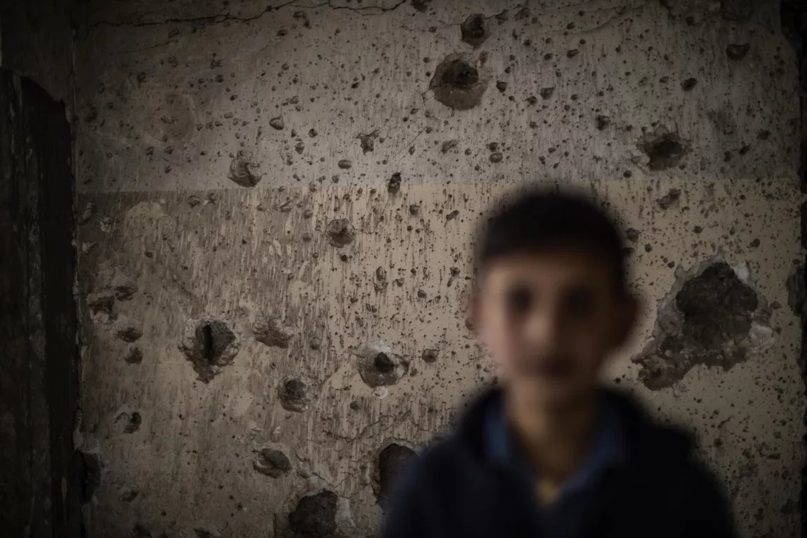 Abdul pose devant un mur endommag&eacute; &agrave; l&rsquo;int&eacute;rieur d&rsquo;une &eacute;cole de Mossoul qui a &eacute;t&eacute; s&eacute;v&egrave;rement touch&eacute;e par les tirs d&rsquo;obus.