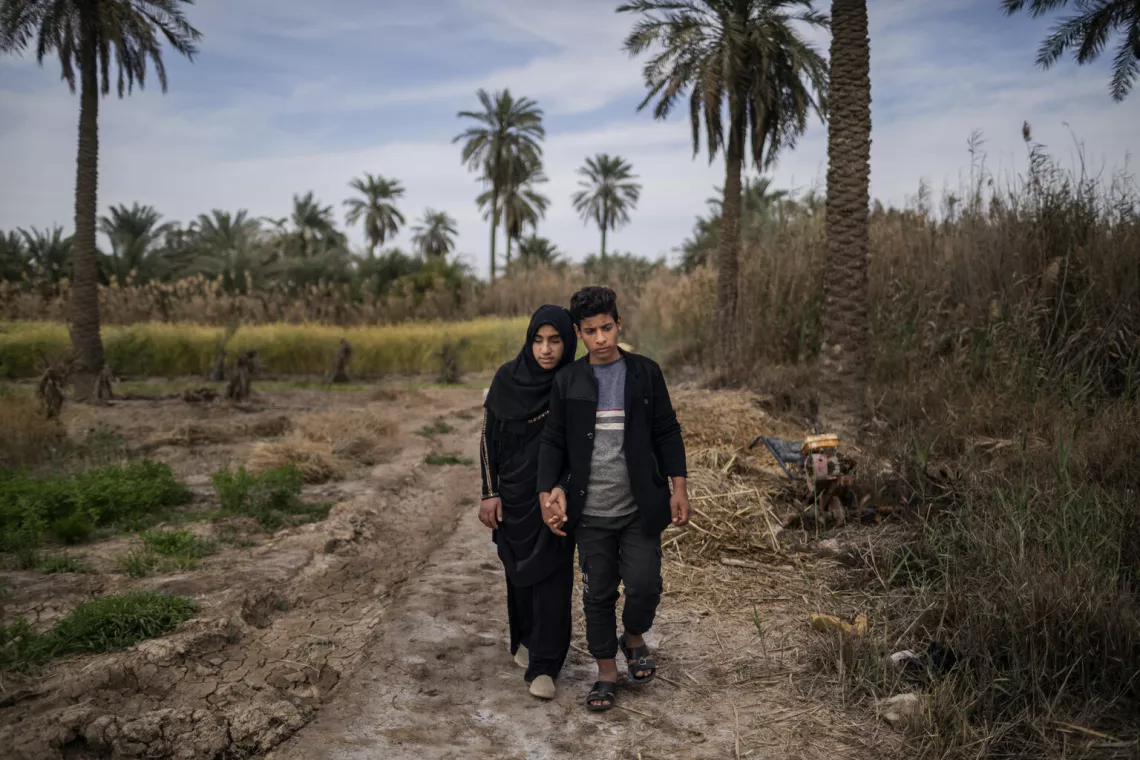 Zainab (à gauche), marche avec son frère, Abdel, à l’extérieur de leur maison à Basra.